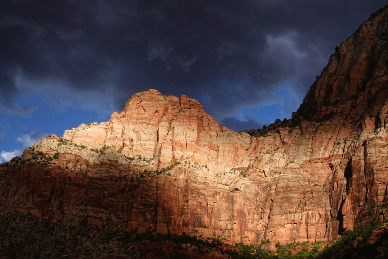 Late-day light on sandstone cliffs, storm clouds  -  from the Museum of Human History, Zion National Park, Utah