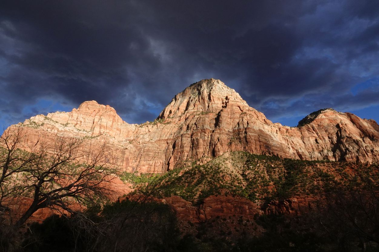 Late-day light on sandstone cliffs, storm clouds  -  from the Museum of Human History, Zion National Park, Utah