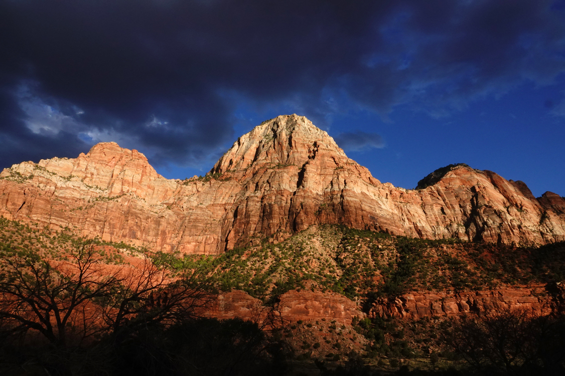 Late-day light on sandstone cliffs, storm clouds  -  from the Museum of Human History, Zion National Park, Utah