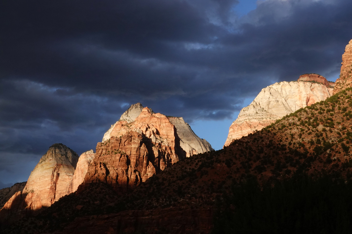 Late-day light on sandstone cliffs, storm clouds  -  from the Museum of Human History, Zion National Park, Utah